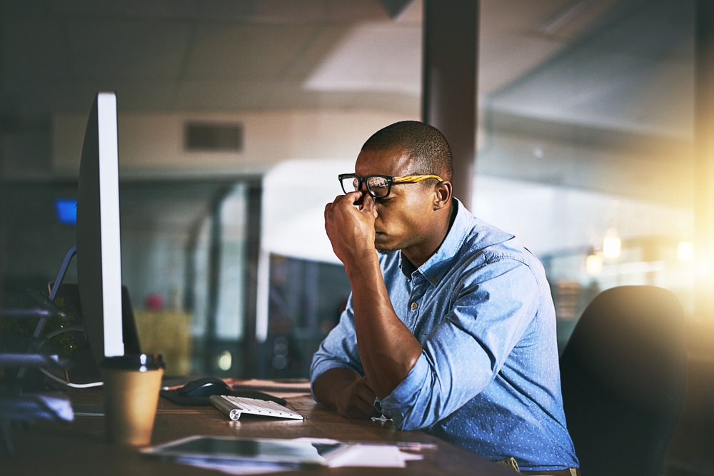 Black business man, stress and fatigue in night, office and headache by computer for project deadline. African businessman, burnout or anxiety in workplace by pc, web design startup and mental health