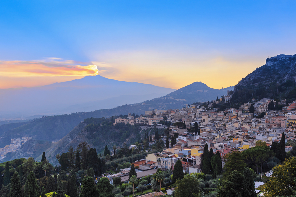 View of the city of Taormina and the active volcano Etna at sunset, Italy