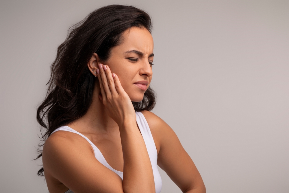 Tinnitus. Profile of sick brunette young woman having ear pain, touching her painful cheek, copy space. Unhappy millennial lady experiencing wisdom tooth pain
