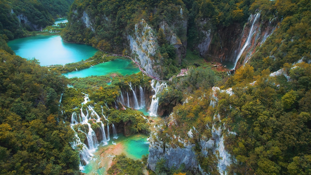 Waterfalls in the autumn forest flowing into lakes. Tourists visit famous Plitvice park in Croatia. Mountain streams with clear water.