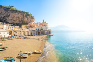 10+ Countries Will Actually Pay You to Move There in 2026 Amalfi Coast in southern Italy, specifically showing a seaside village nestled along the dramatic cliffs and turquoise waters.
