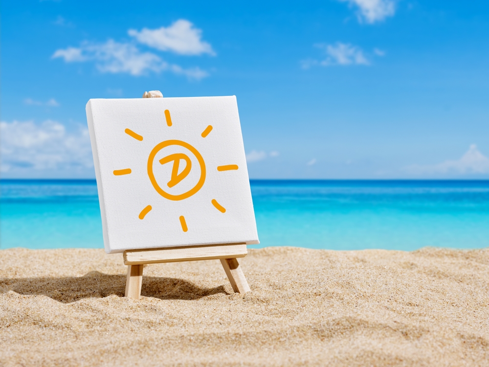 Vacation, holiday, sun and vitamin D intake. Heath care concept. A canvas on an easel with sun and letter D symbols on the sands of a beach.