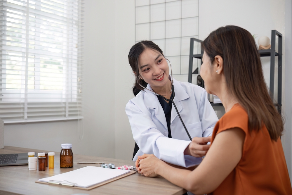 Female doctor and elderly female patient who are undergoing their annual health check-up at the clinic, using a stethoscope to examine patients

