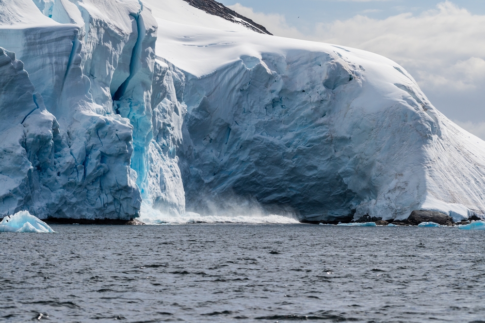 Telephoto of a giant chunk of ice calving off an ice sheet. Graham Passage, near Charlotte Bay, on the Antarctic Peninsula