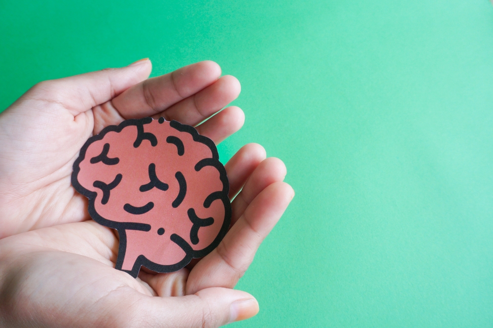 Woman hands holding human brain shape made from paper on light blue background. Awareness of Alzheimer, Parkinson's disease, dementia, stroke, seizure or mental health. Neurology and Psychology care.