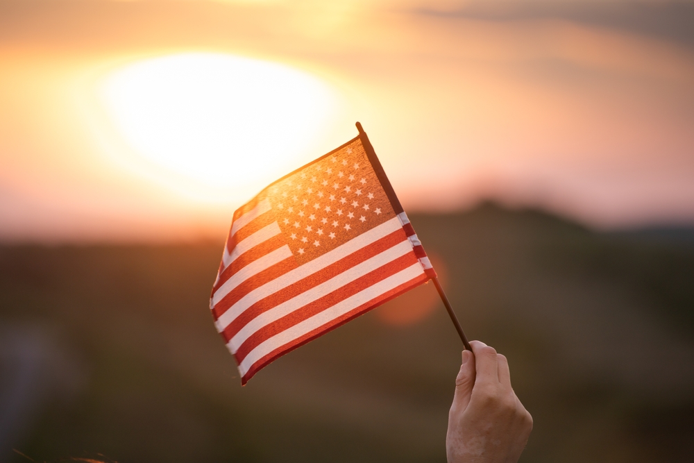 Close up on USA flag in a hand of a persone. Independence Day or traveling in America concept.