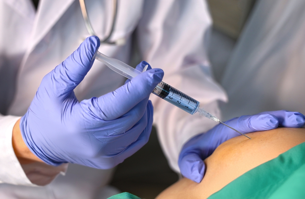 Close up of doctor's hand giving patient an injection in the knee
