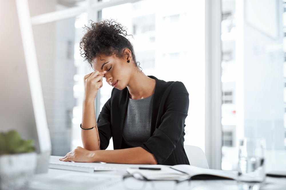 Business, black woman and tired with headache in office from migraine, overworked and stress for work deadline. Professional, employee and mental health with anxiety, burnout and fatigue from project