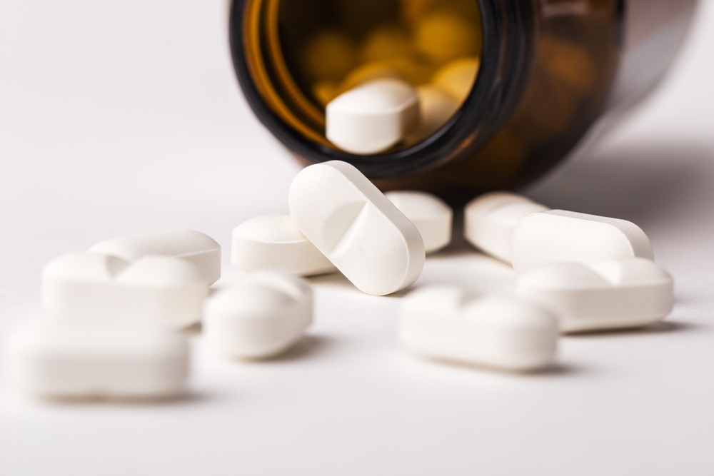 Close up magnesium supplements fell out of a glass bottle on a white background. Food additives. Selective focus.