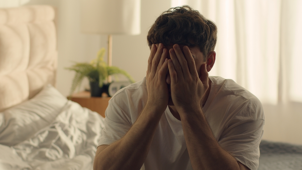 Caucasian man guy male bedroom despair hopeless situation problems difficulties crisis pain holding head grief anxiety distraught displeased frustration disappointment exhaustion distress overwhelmed