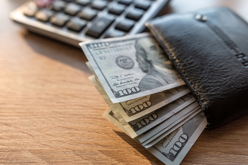 black male leather wallet and us dollar money with calculator on desk. Financial saving concept