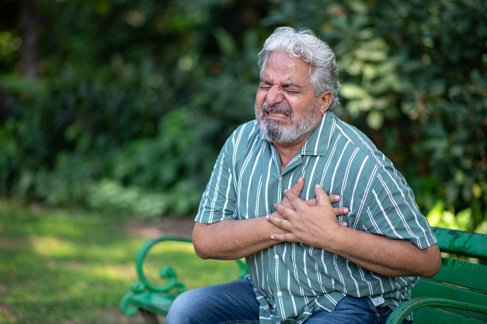 Heart attack concept.. Indian Senior man suffering from chest pain outdoor in park,