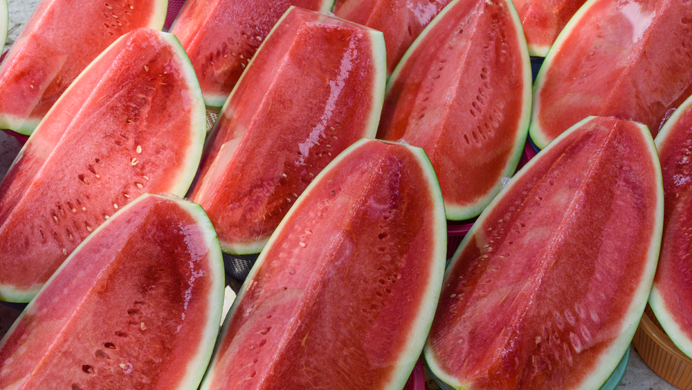 Close-up view group of fresh raw slice cut, pre-cut seedless watermelon protected in plastic wrapper on display at the local street Fruits stall in Geylang, Singapore. Fresh take away, to-go fruits