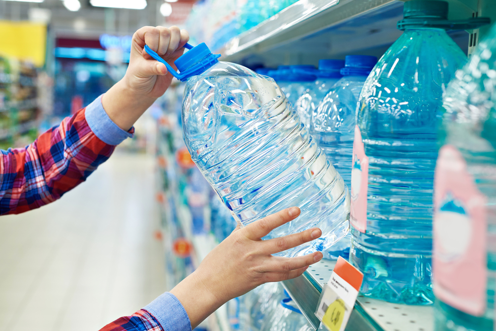 Woman with bottle drinking water in shop
