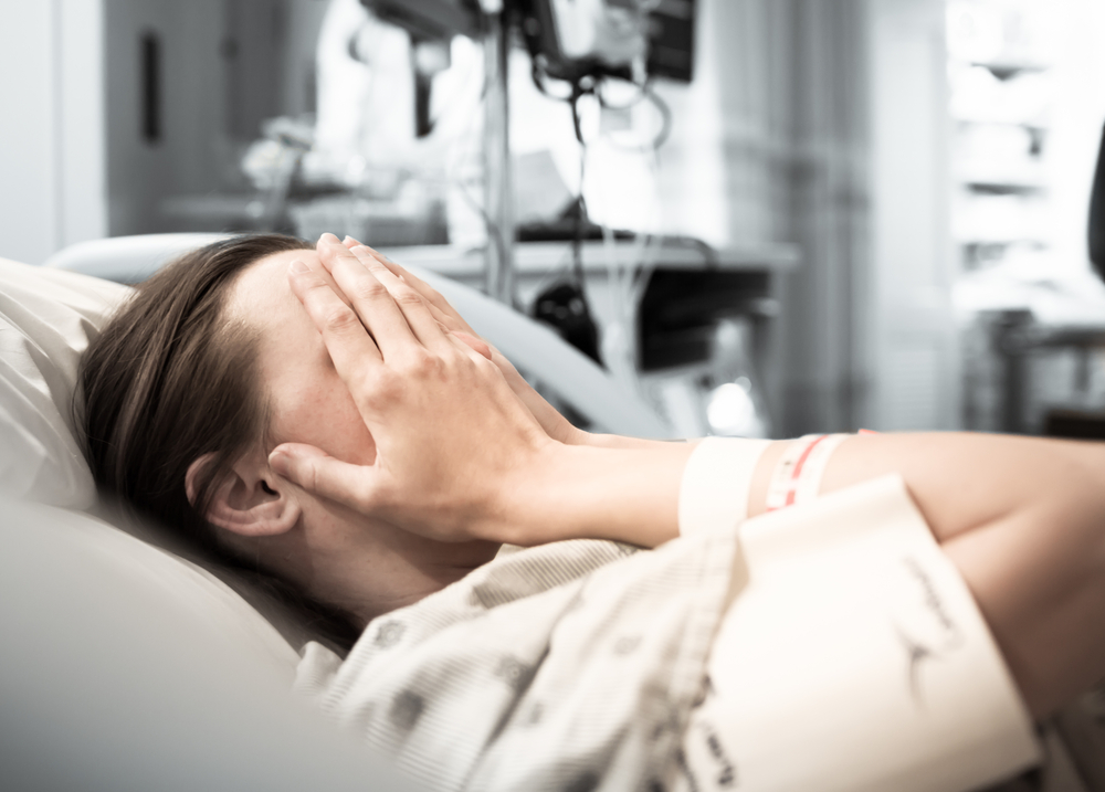 Young woman patient lying at hospital bed feeling sad and depressed worried. Disease feeling sick in health care and clinical attention concept
