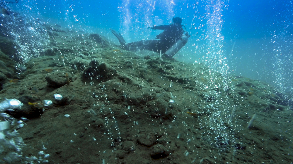 Scuba diver relaxing in hot water bubbles at underwater volcano, Pulau Weh