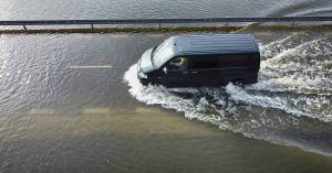 Van driving across flooded bridge