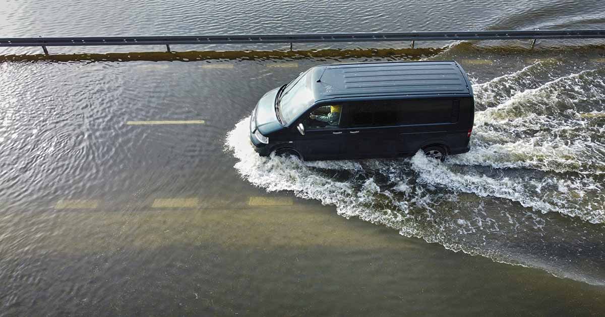 Van driving across flooded bridge