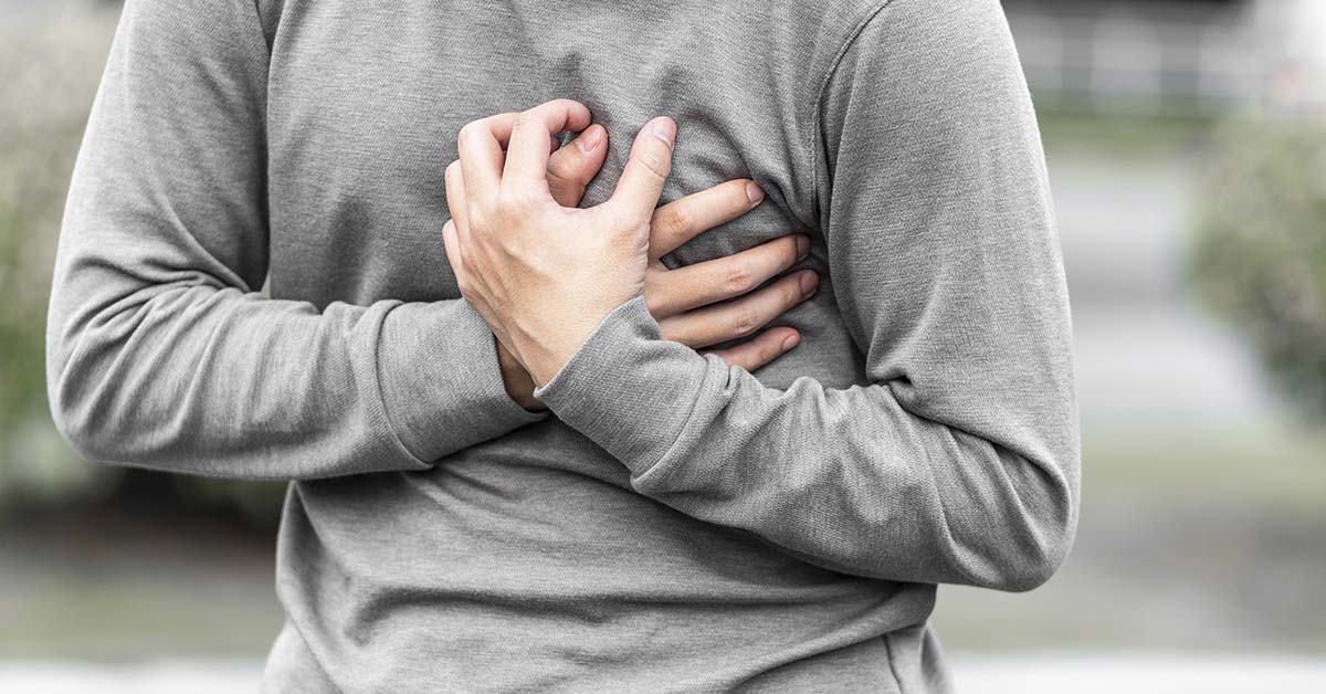 man clenching hands over chest. Heart attack symptom concept