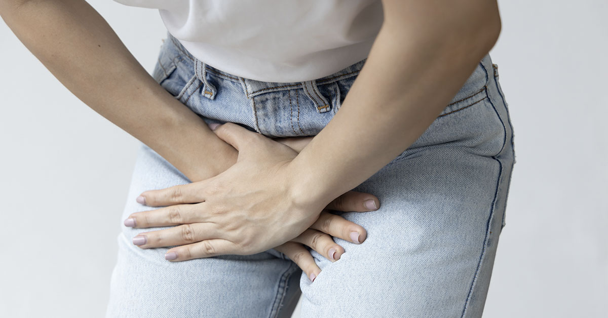 Woman with hands placed over groin area due to UTI pain