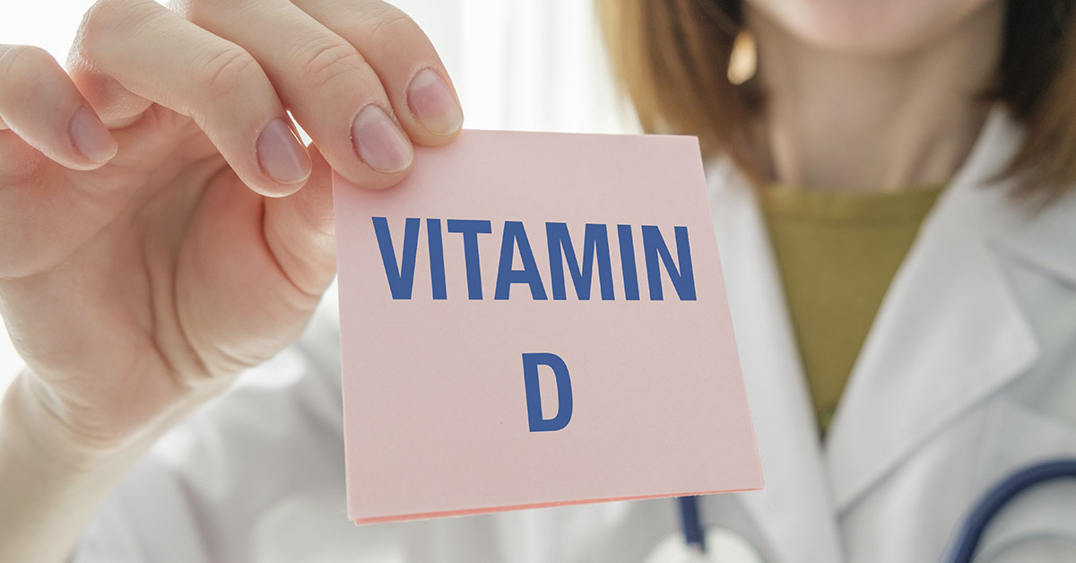 Doctor holding up pink card with Vitamin D printed on it