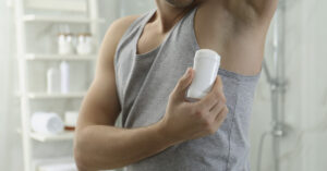 Major Deodorant Recall: 67,000 Units Pulled From Walmart, Dollar Tree, and Amazon Man putting on deodorant