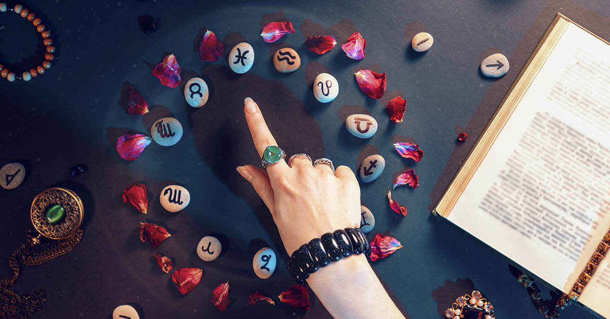woman pointing to small stones with Zodiac symbols on them