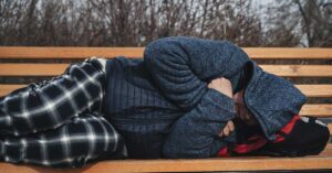 Mandated Treatment & Forced Removal: Trump’s New Homelessness Policy Divides Nation homeless man sleeping on a bench