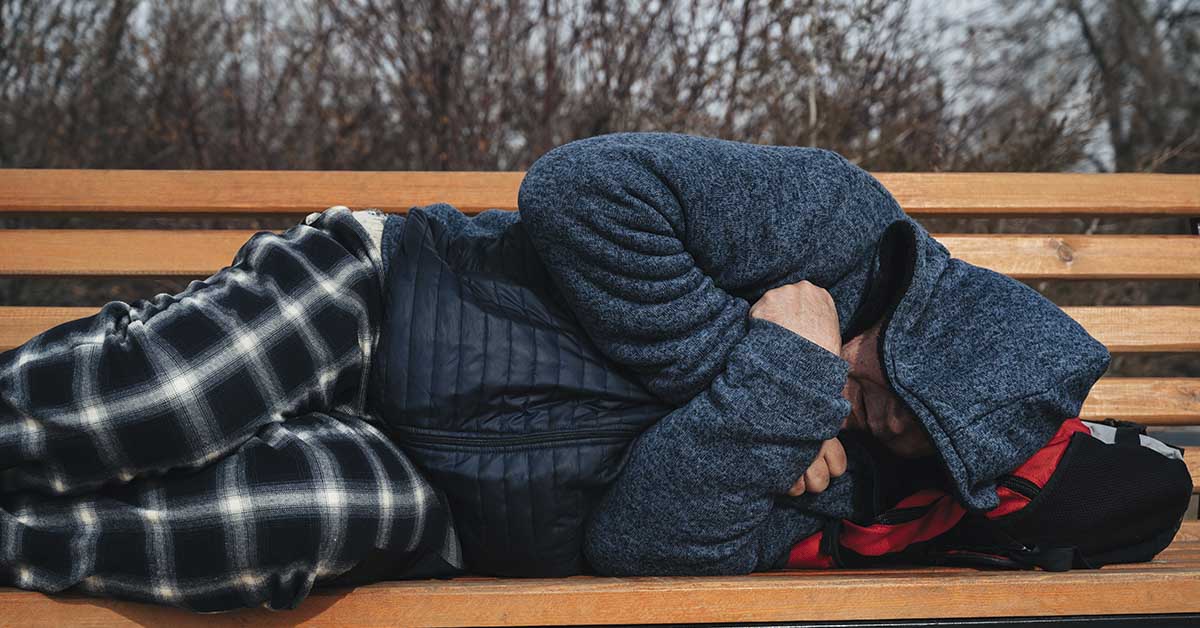 homeless man sleeping on a bench