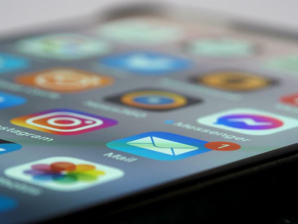 Close-up view of a smartphone screen displaying various colorful app icons including social media, messaging, and other popular mobile applications, illustrating the multiple online platforms that could be vulnerable to password attacks.