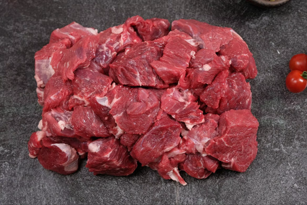 Chunks of raw red meat on a dark surface, representing the red meats linked to increased risk in young patients.