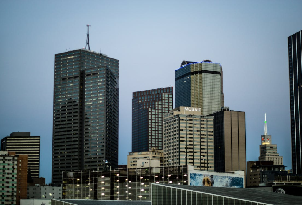 Black Curtain Glass Building Beside Four Curtain Glass Buildings Under Blue Sky
