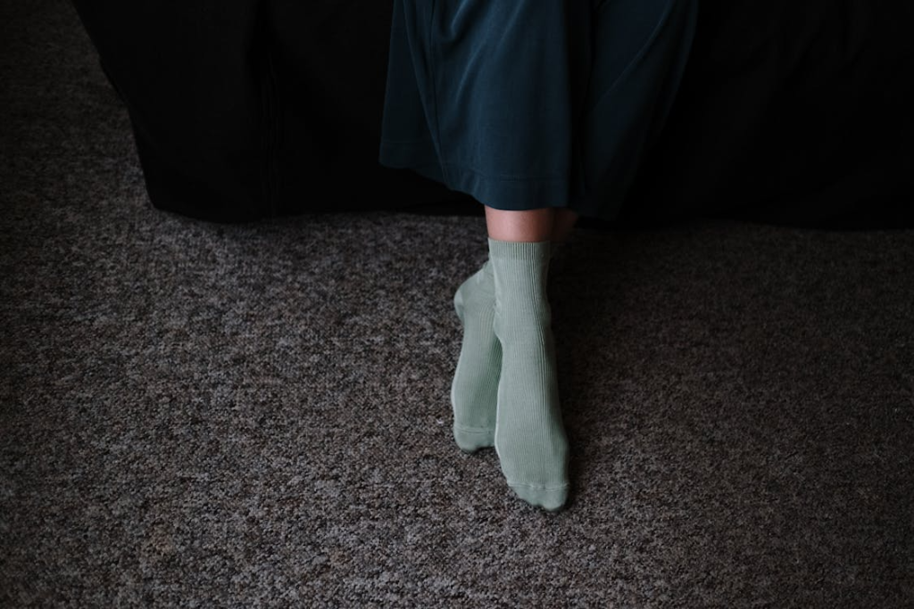 Crop woman in socks on rug at home
