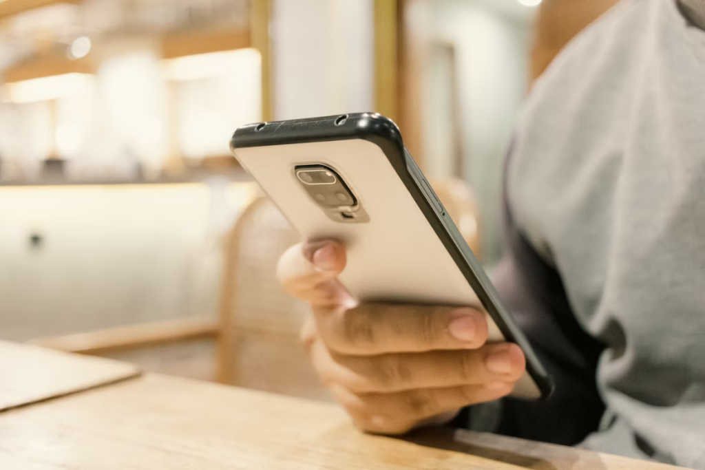 Person using smartphone to find hidden cameras connected to Wi-Fi network.