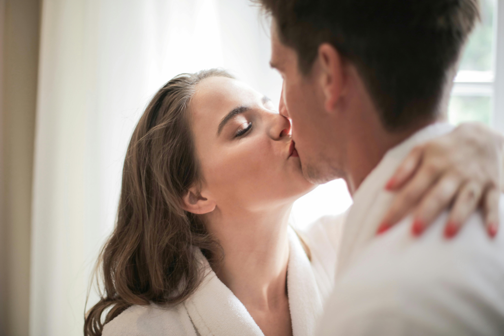 Young couple sharing an intimate kiss indoors as dopamine and oxytocin flood their brains.