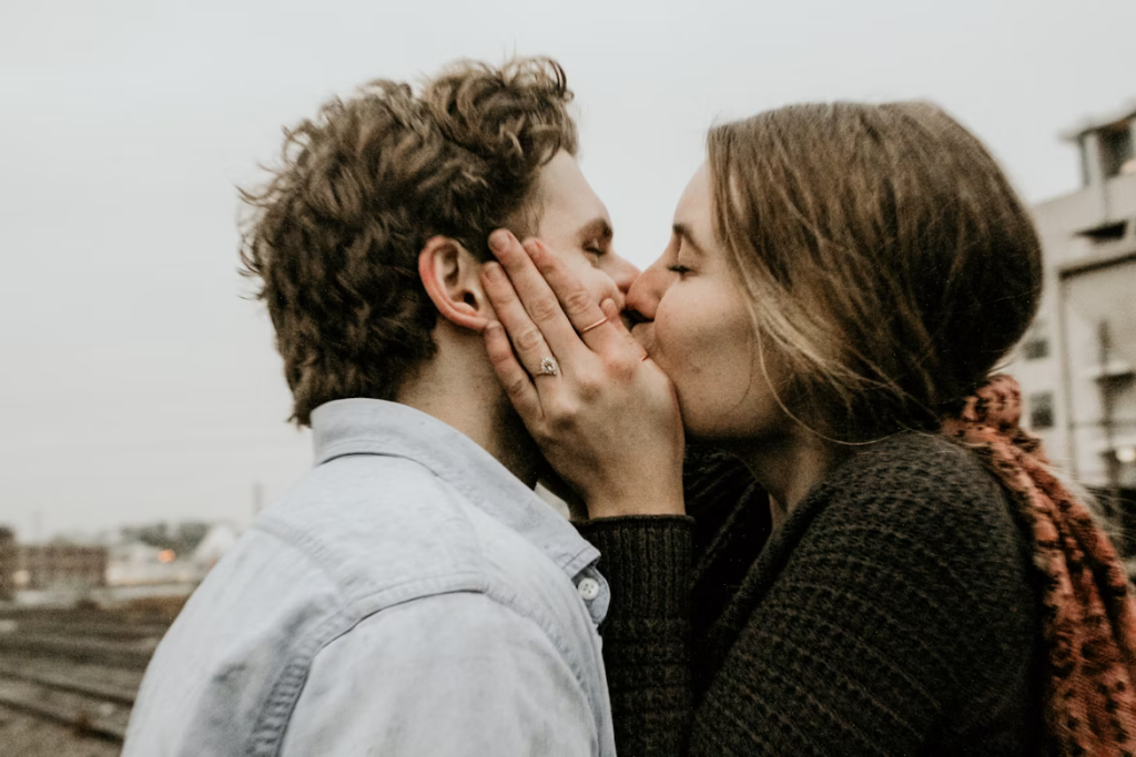 Woman tenderly cups man's face as they kiss, burning calories while exchanging bacteria that strengthen their immune systems.