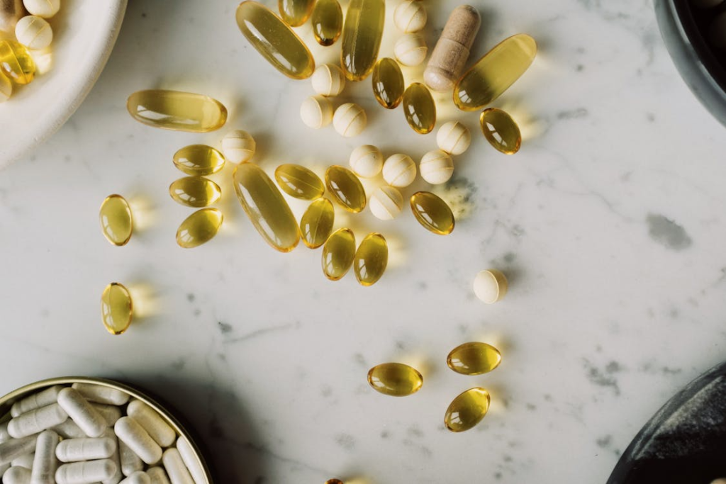 Capsules in yellow shell and several dragees scattered on white table