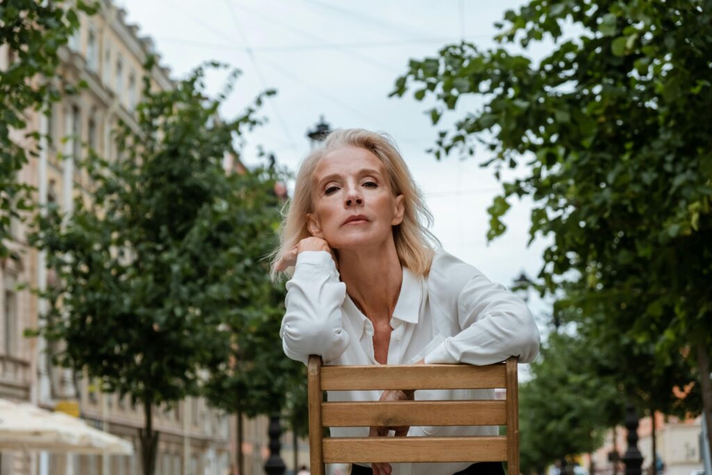 Woman in White Dress Shirt Sitting on Brown Wooden Bench 
