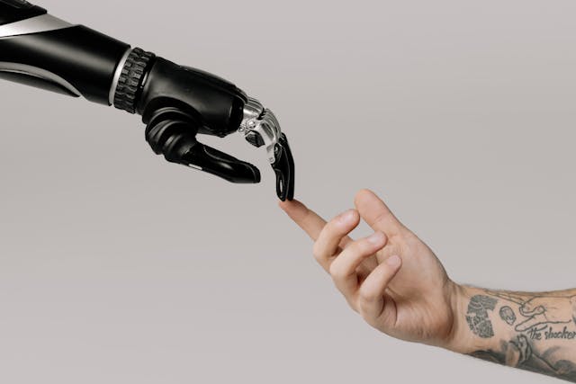 robotic hand touching hand of tattoed human