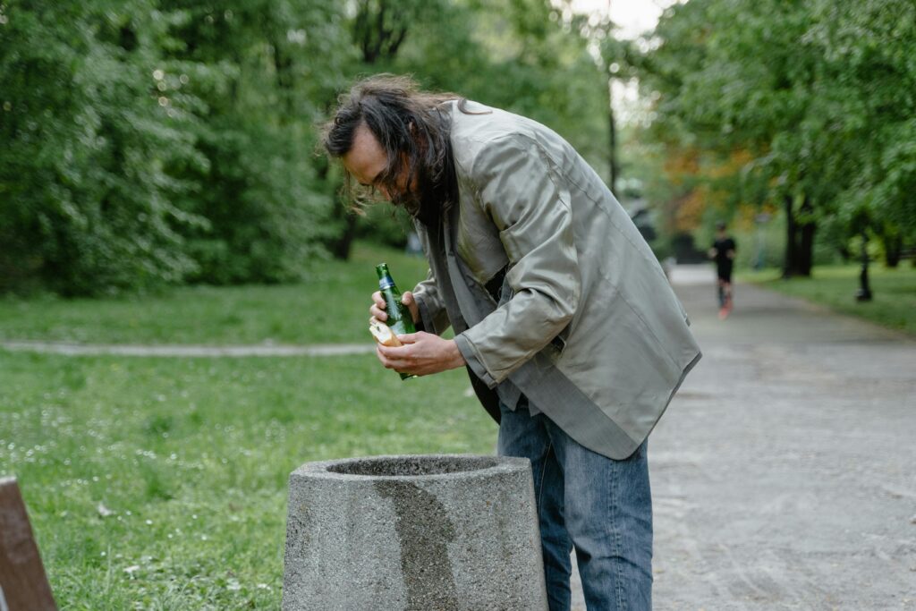 Homeless Man picking up Leftovers on a Trashbin
