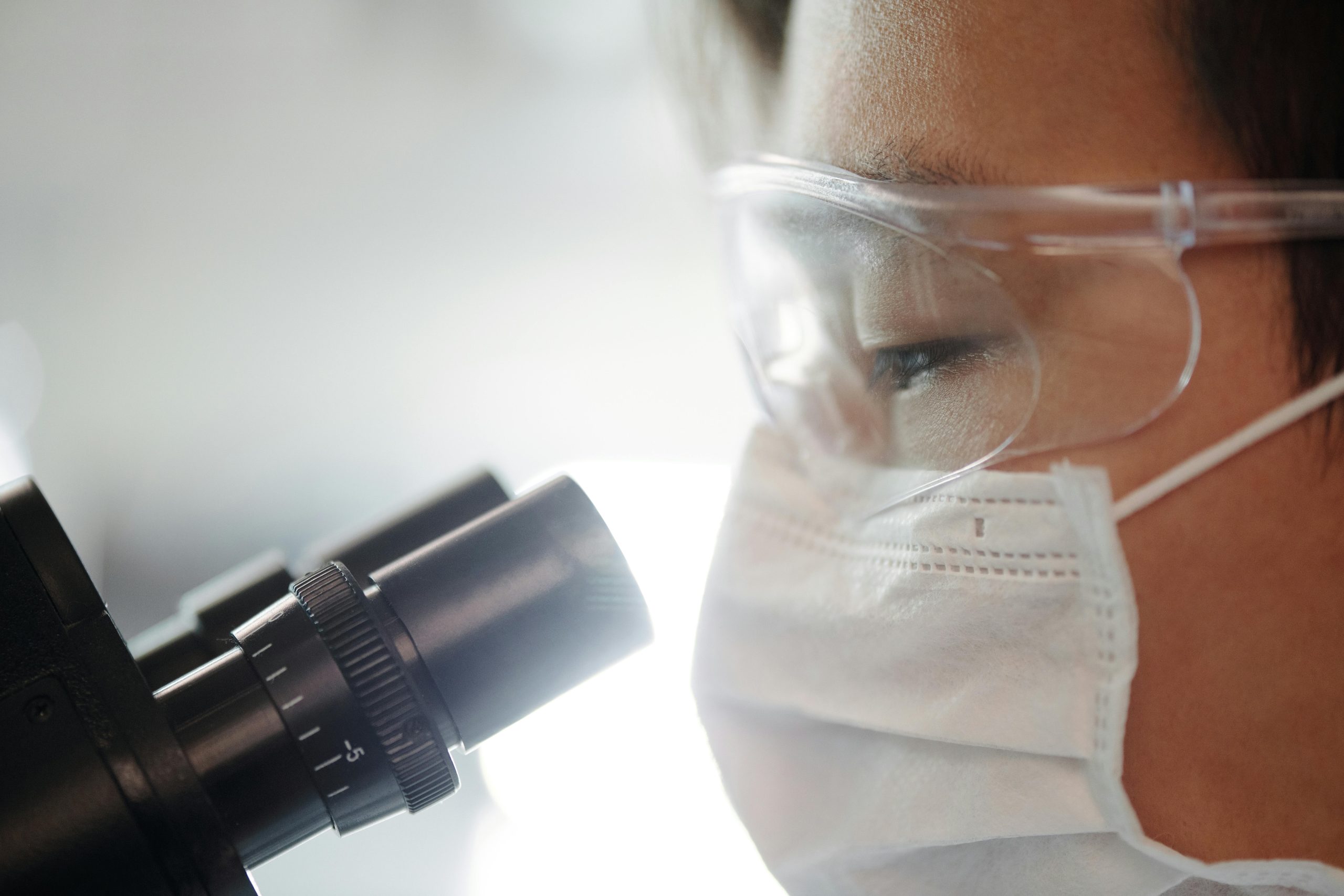 Healthcare professional examining urine samples under laboratory microscope for accurate diagnosis.