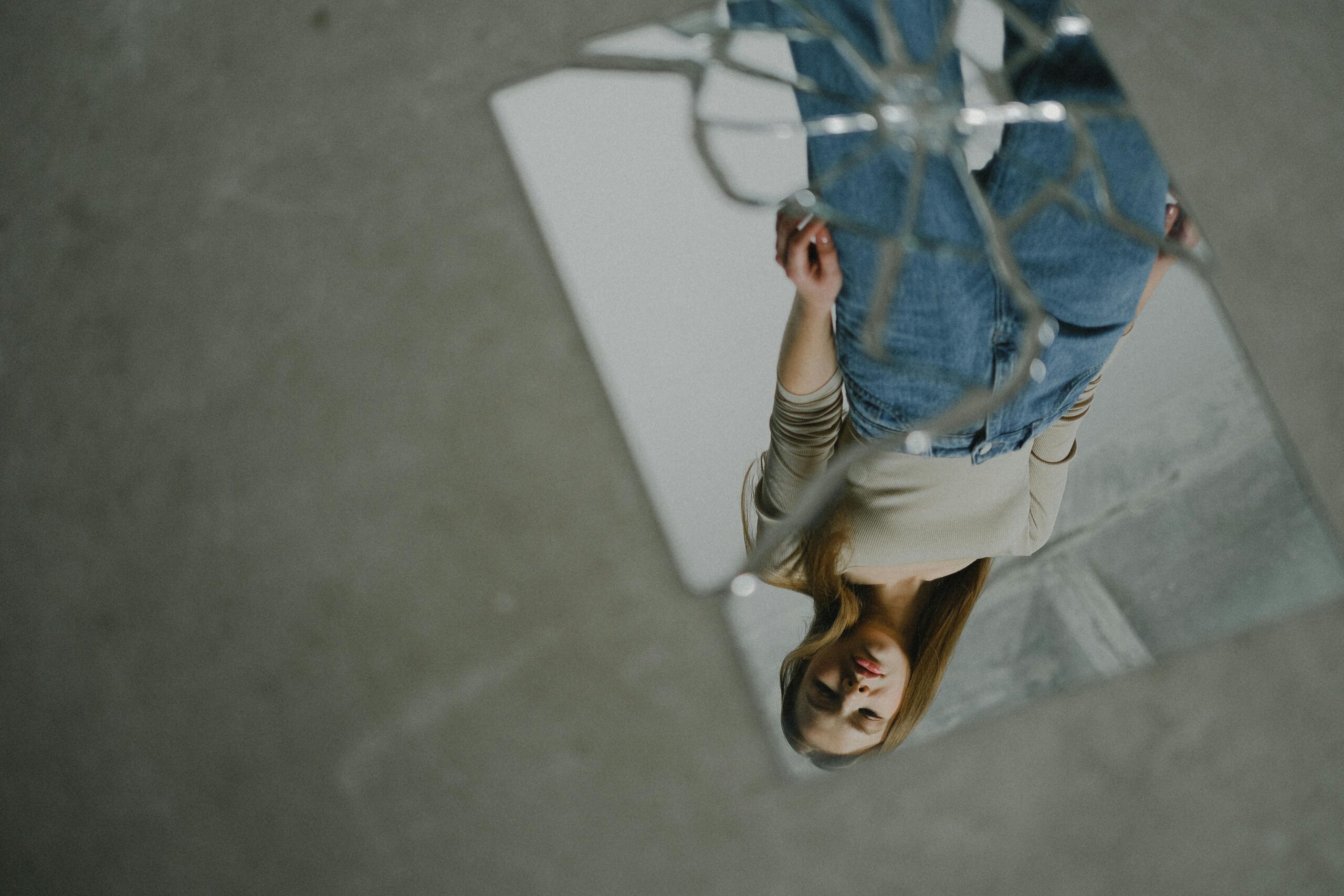 An upside down reflection of a teenage girl in broken mirror