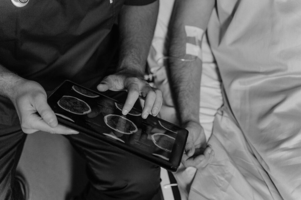 Grayscale Photo of a Doctor Using a Digital Tablet