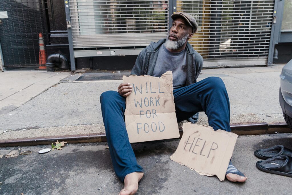 Man Sitting on Sidewalk with Cardboards
