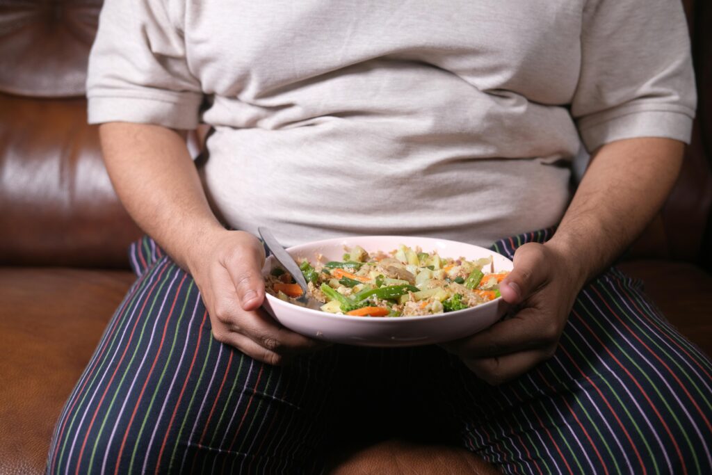 Person Holding a Bowl of Food with Spoon