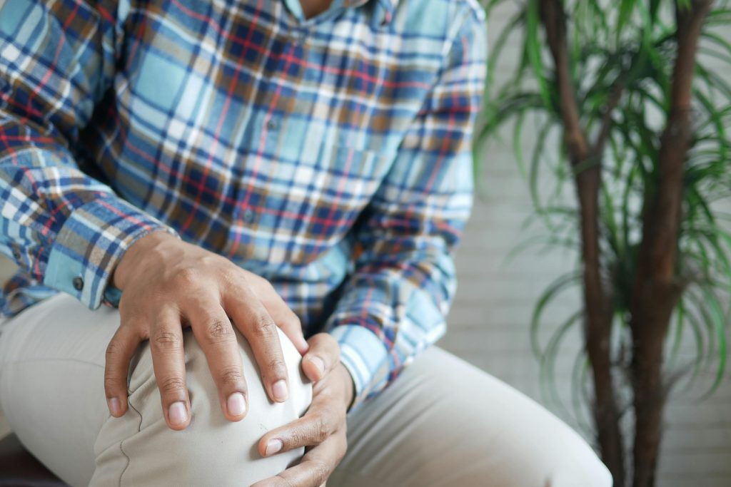 A Person in Plaid Long Sleeves Holding His Knee
