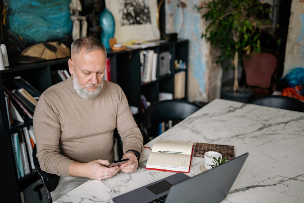 An Elderly Man Busy with His Cellphone while Sitting on a Chair