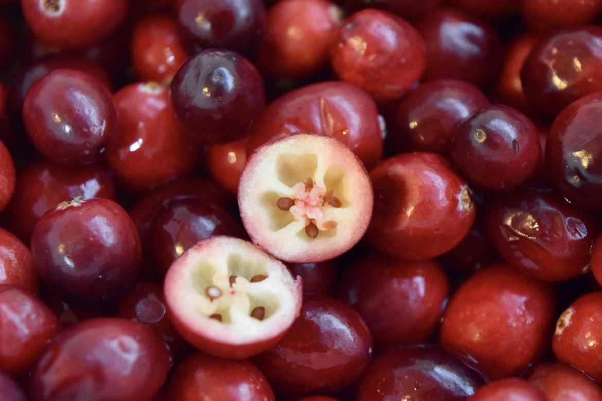 Fresh red cranberries with cross-section showing interior, highlighting natural supplements for UTI prevention.