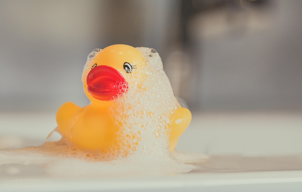 Rubber duck surrounded by bubble bath foam, illustrating bath products to avoid.
