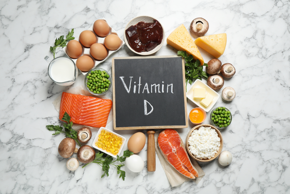 Flat lay composition with products rich in vitamin D on white marble table
